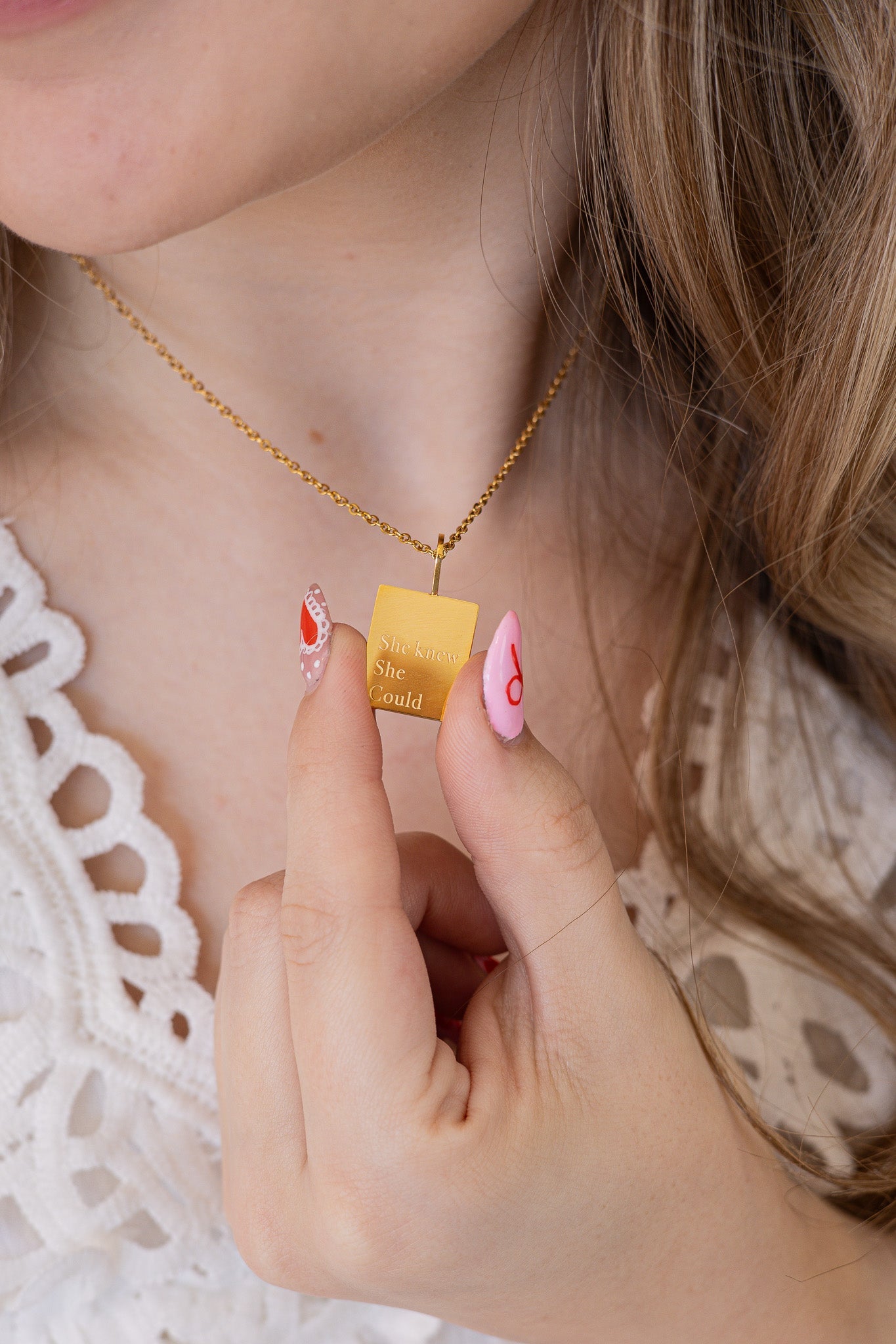 Person wearing a gold necklace with a small yellow pendant.