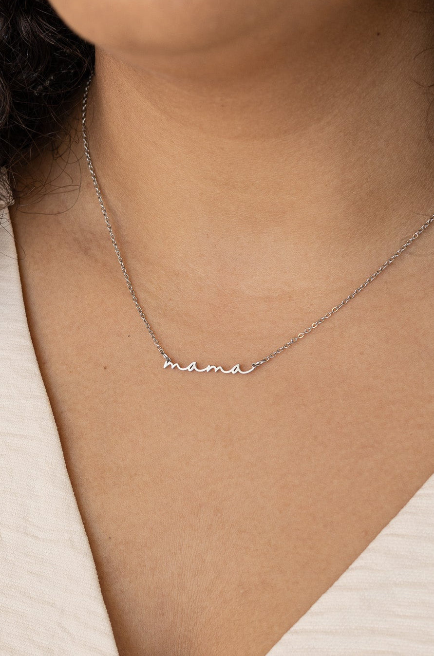 Silver 'mama' necklace on a person's neck with a neutral background
