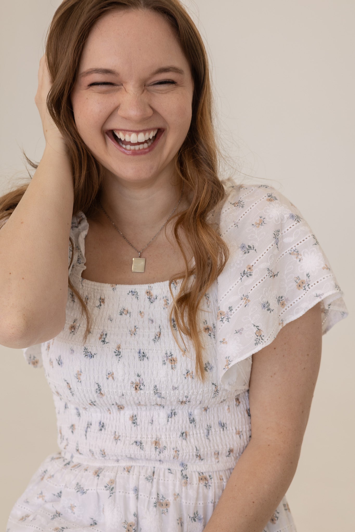 Woman wearing a white floral dress with a plain background