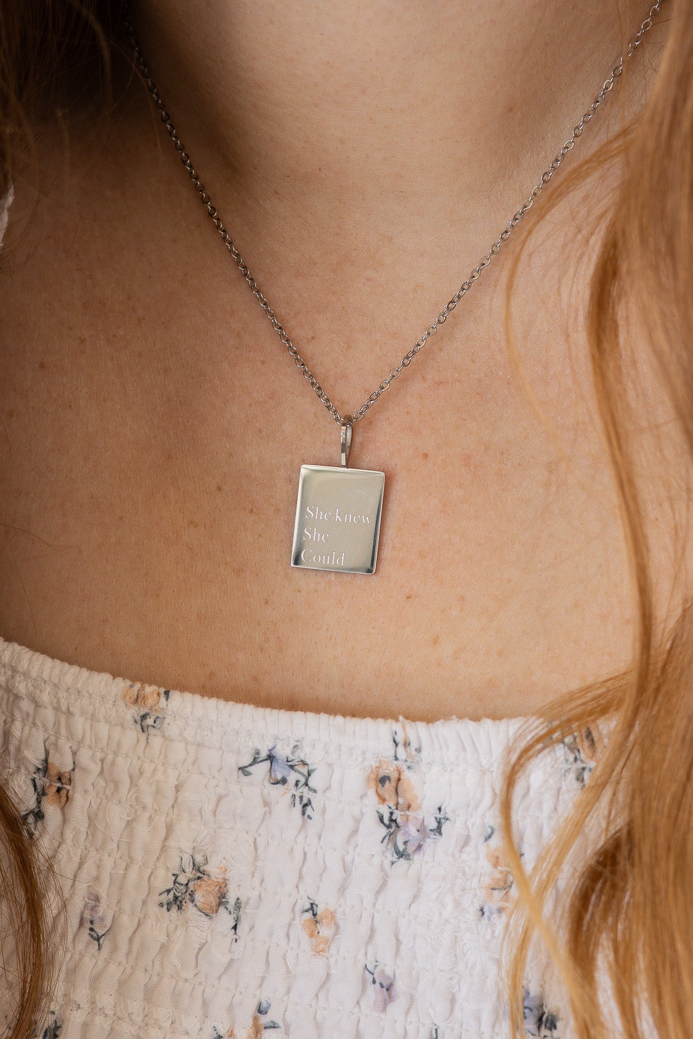 Necklace with a pendant worn by a person with floral-patterned clothing.