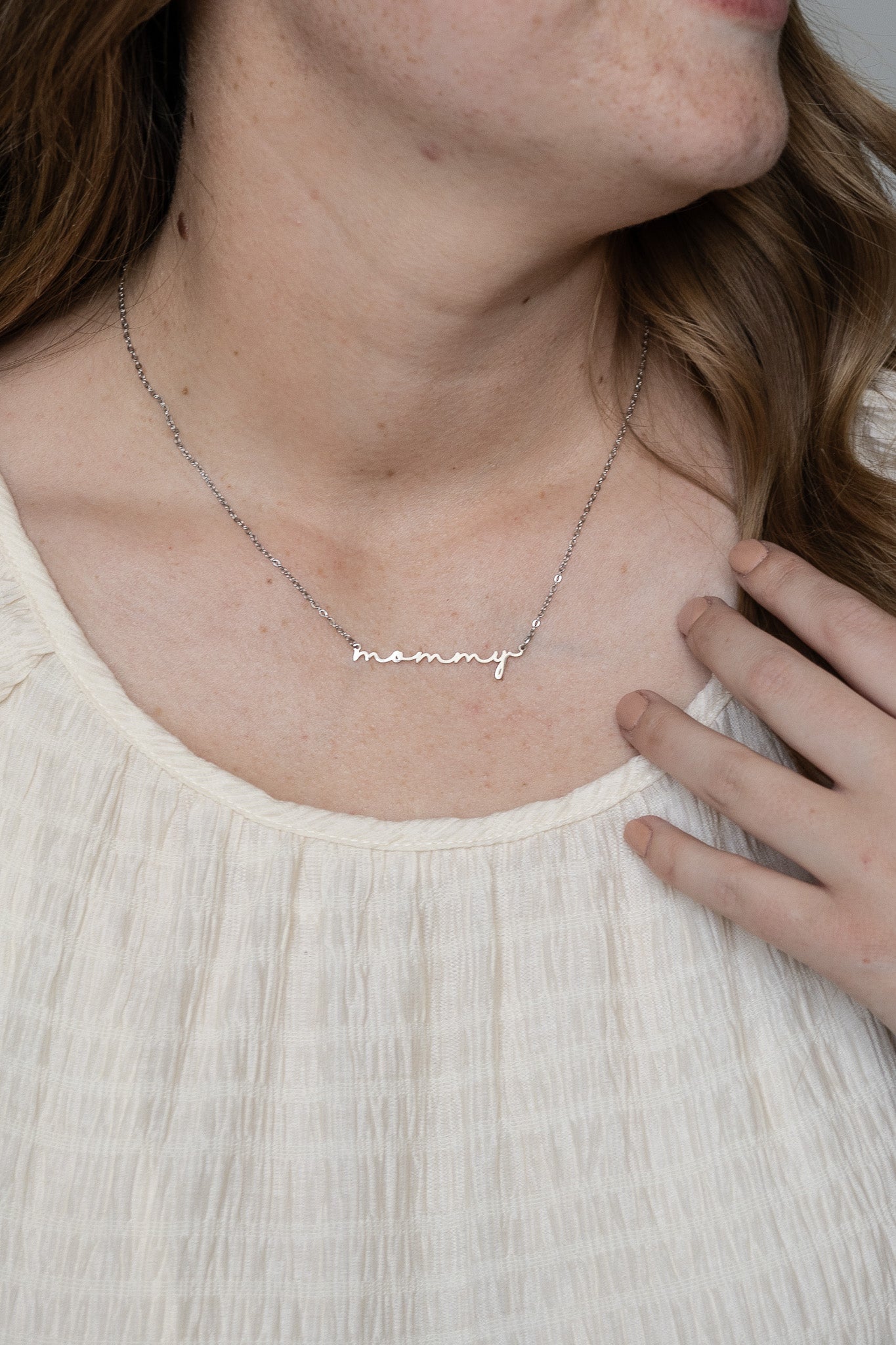 Necklace with 'mommy' pendant worn by a person