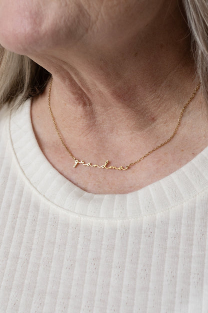 Gold necklace with engraved name on a person wearing a white shirt
