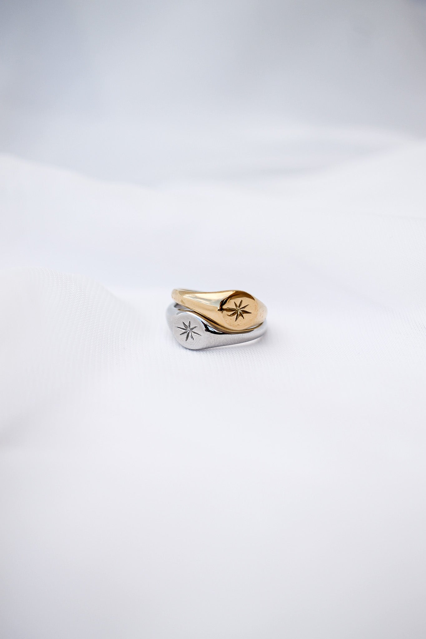 Two rings, one gold and one silver, on a light gray background