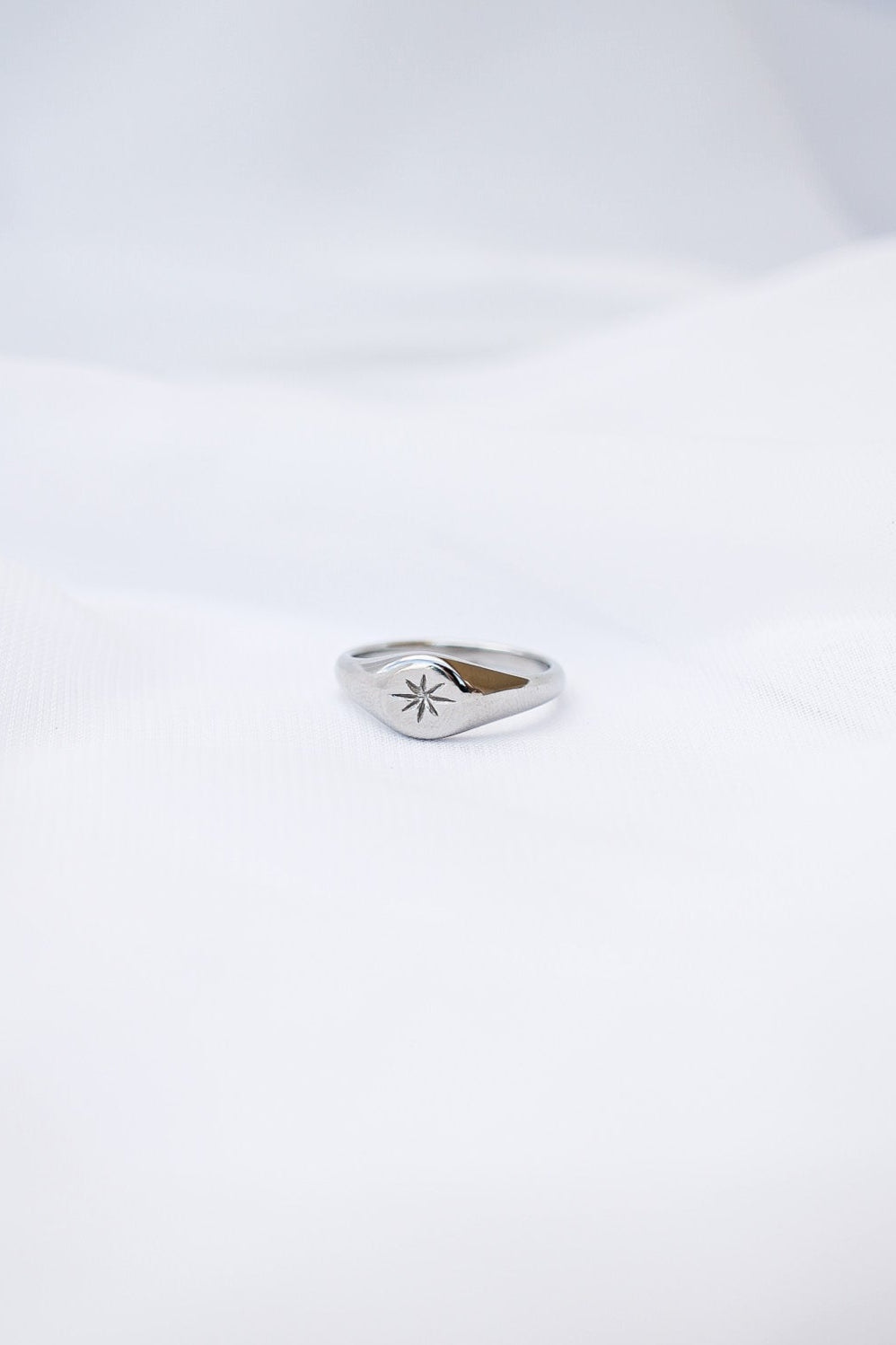 Silver ring with a star design on a white background