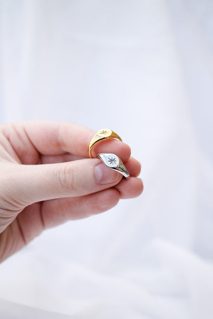 Gold ring with a diamond on a finger against a white background