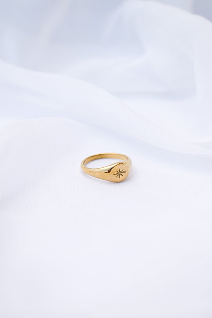 Gold ring with a star design on a white background