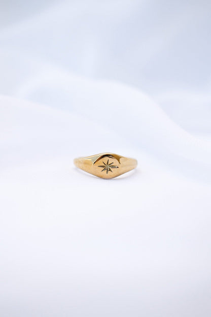 Gold ring with a star design on a light gray background