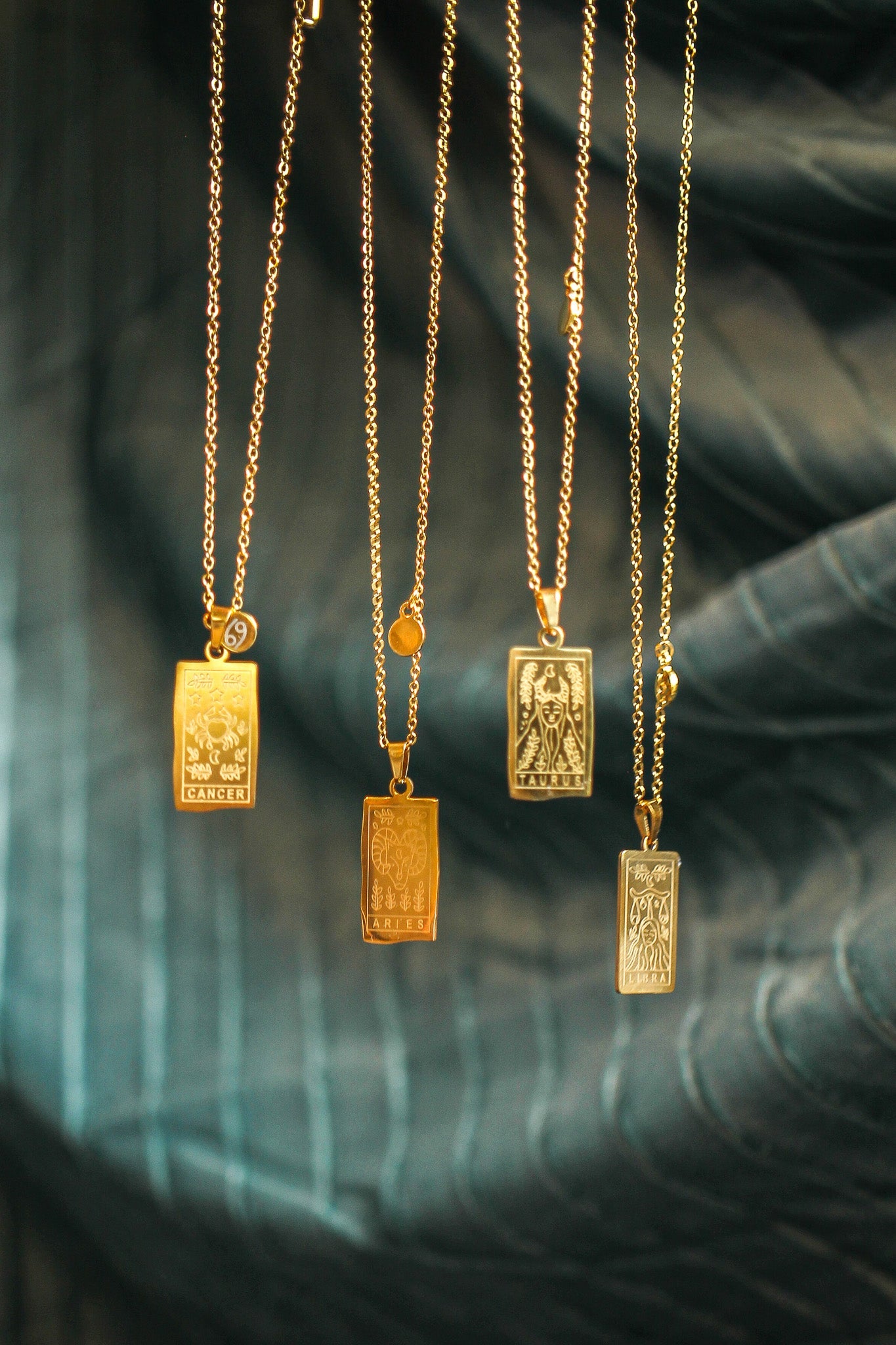 Gold necklaces with rectangular pendants on a dark background