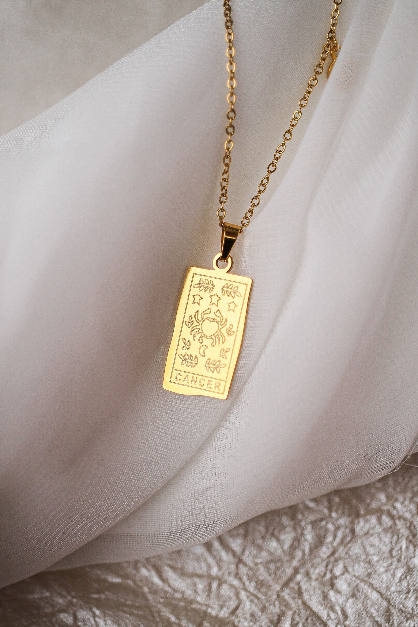 Gold pendant necklace on a soft fabric background