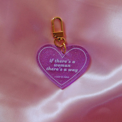 Purple heart-shaped keychain with gold clasp on a pink fabric background