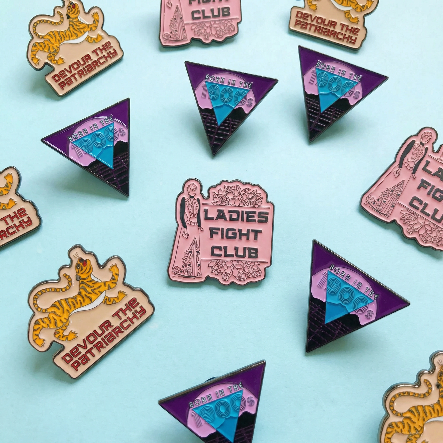 Collection of feminist-themed pins on a light blue background