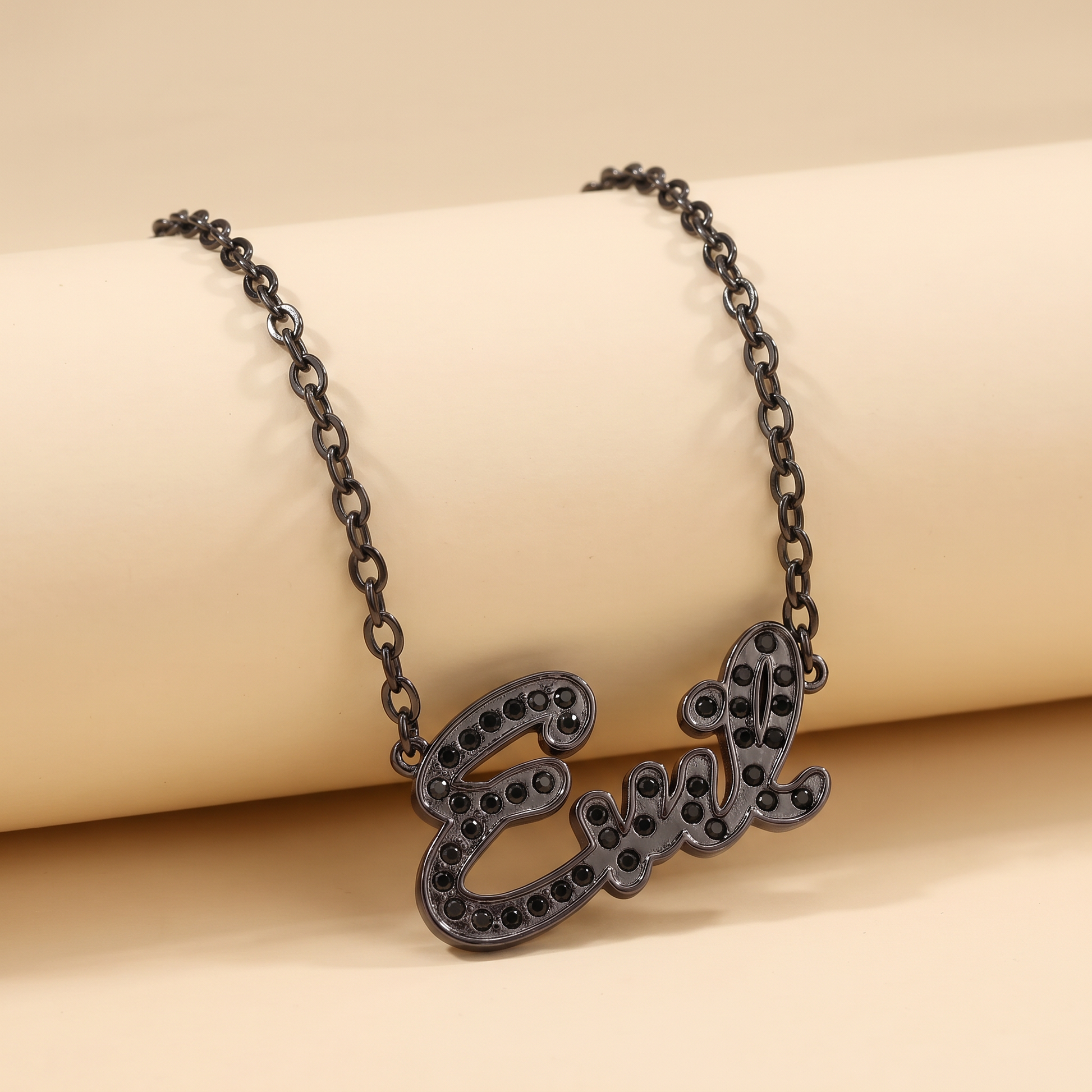 Black chain necklace with 'Eve' pendant on a beige background