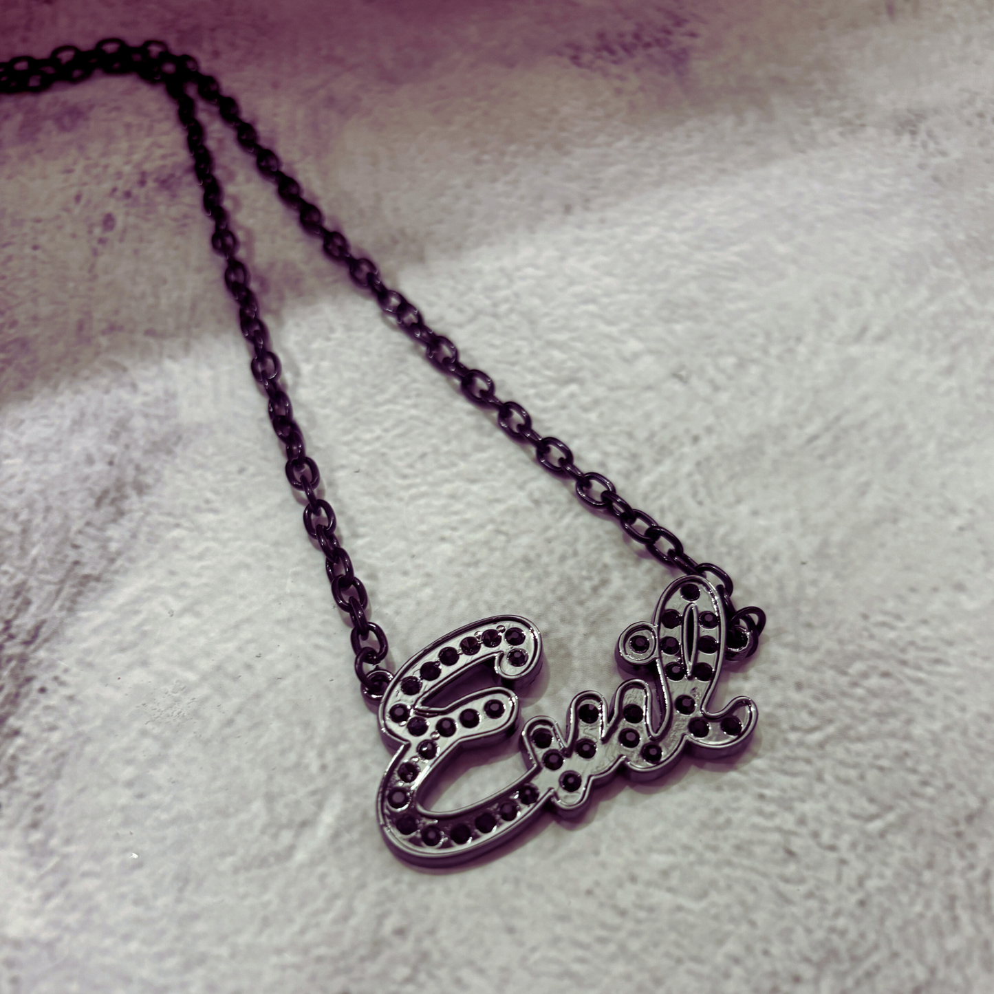 Necklace with 'Evel' pendant on a textured surface