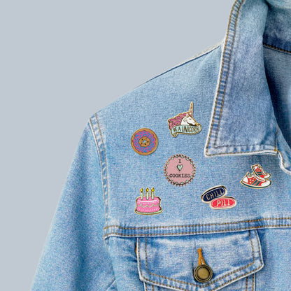 Denim jacket with various colorful pins on a light gray background