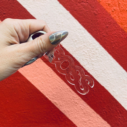 Clear plastic visor held by a hand against a red and white striped background
