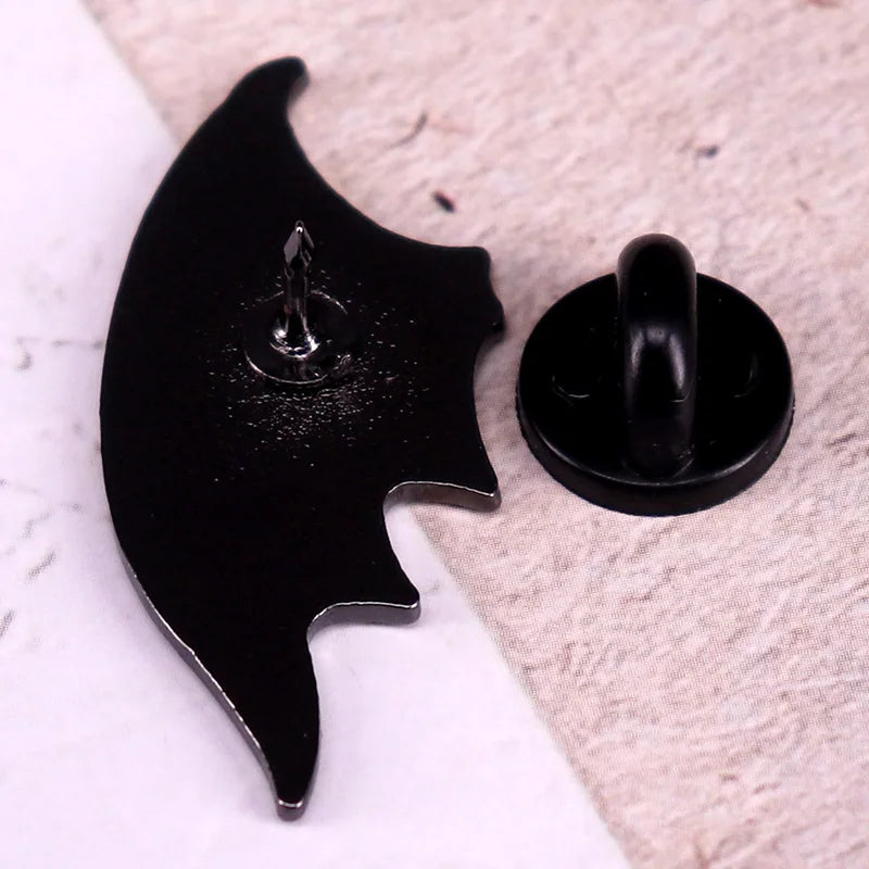 back side of a black bat-shaped pin on a textured surface