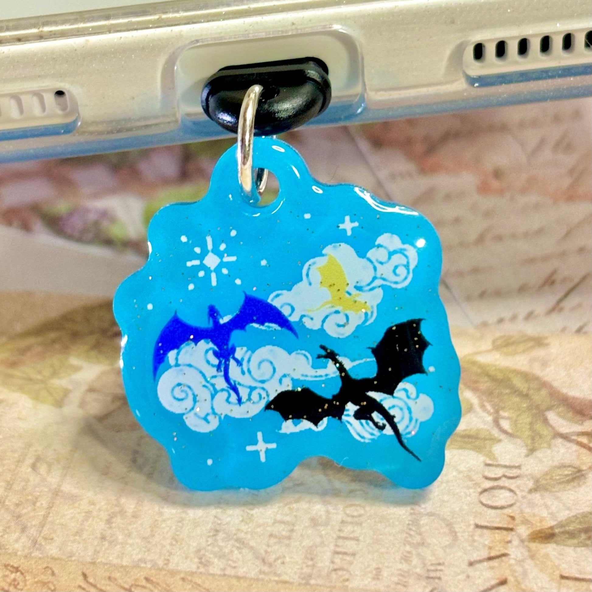 Blue dragon-themed kindle charm attached to a metallic object with a blurred background