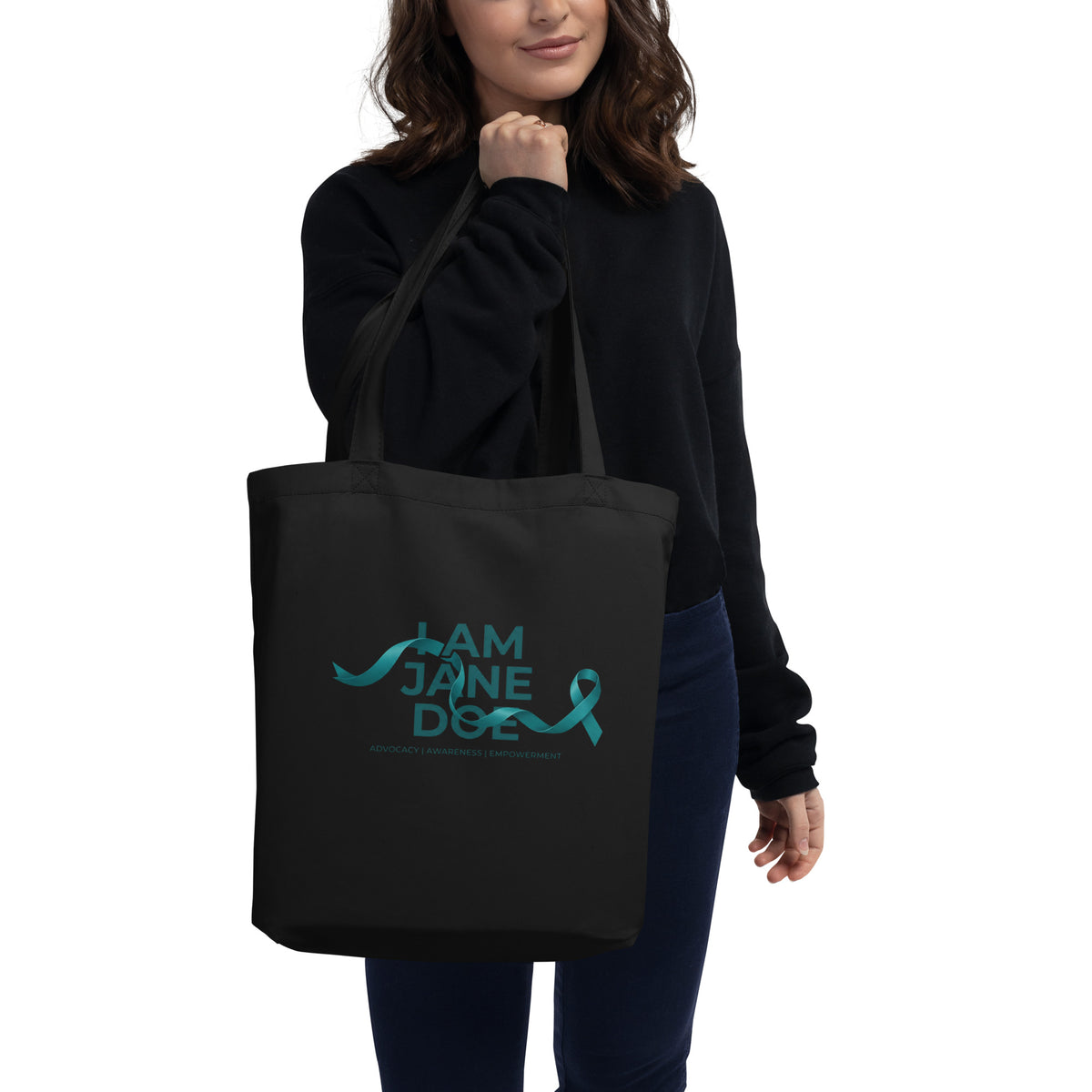 Person holding a black tote bag with 'I AM JANE DOE / ADVOCACY AWARENESS EMPOWERMENT' text in blue.