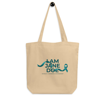 A beige canvas tote bag with two shoulder straps, featuring a teal graphic print on the front that reads 'I AM JANE DOE / ADVOCACY | ACCOUNTABILITY | EMPOWERMENT' with a teal ribbon shown against a plain white background.