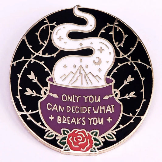 A circular enamel pin featuring a black background with a silver-toned border, a purple cauldron containing white steam with mountains and stars, a red rose at the bottom, and the text 'ONLY YOU CAN DECIDE WHAT BREAKS YOU'.