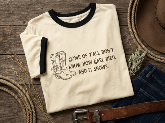 A cream ringer t-shirt with black trim and a western-themed graphic print featuring cowboy boots and the quote 'SOME OF Y'ALL DON'T KNOW HOW EARL DIED. AND IT SHOWS.