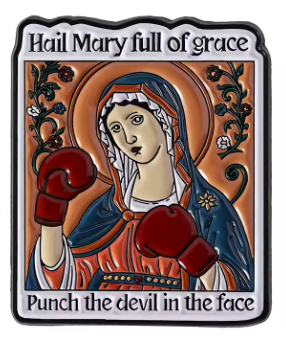 A square decorative enamel pin featuring a stylized religious illustration of Mary with boxing gloves. The top text reads 'Hail Mary full of grace' and the bottom text reads 'Punch the devil in the face.