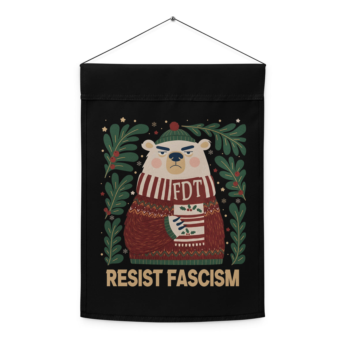 A black hanging fabric banner or wall hanging with a printed illustration of a bear wearing a red and white striped sweater that says 'FDT' and a green hat, surrounded by green leaves and the text 'RESIST FASCISM' at the bottom.