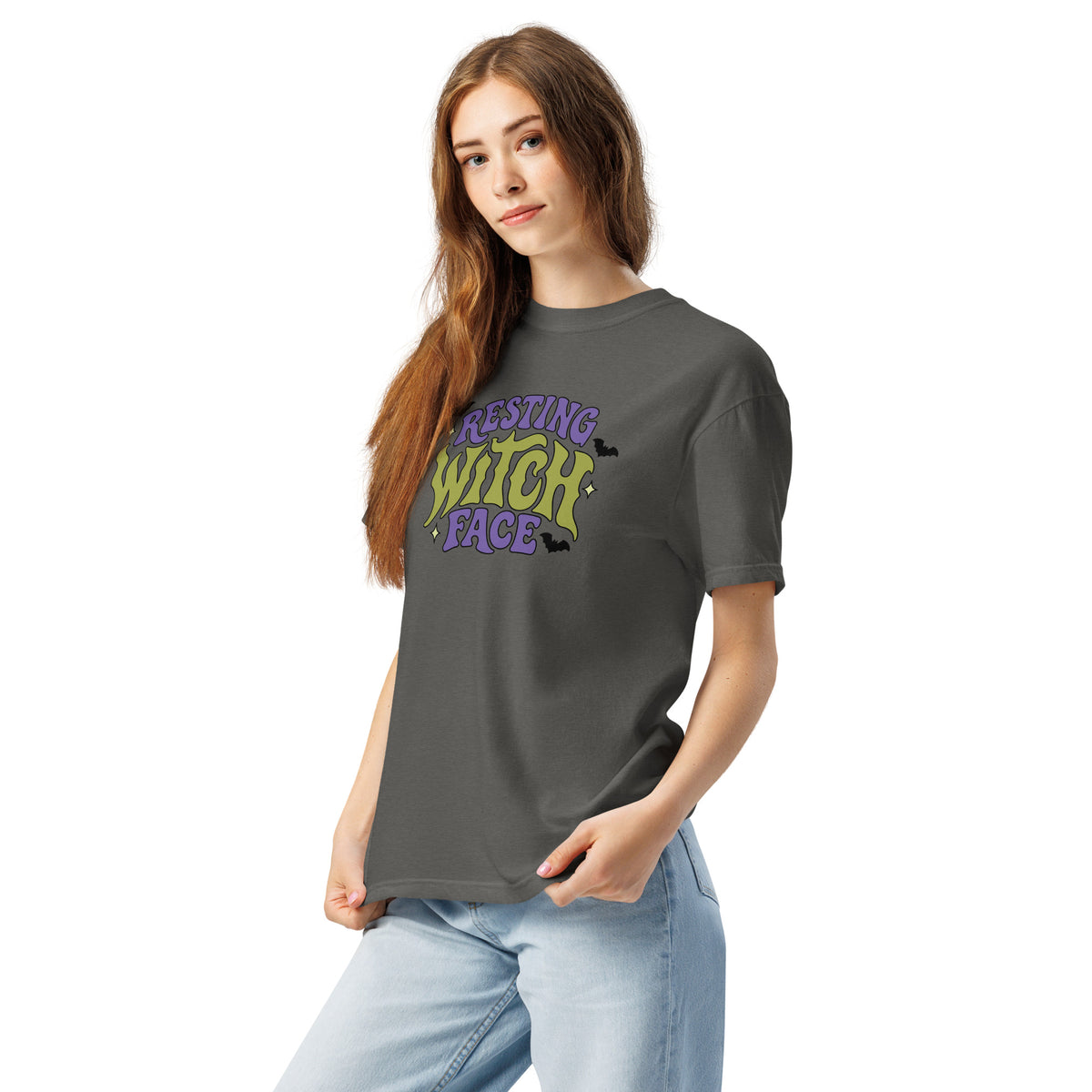 A woman modeling a dark gray t-shirt with the text 'REST WITCH FACE' printed on the chest in black and green, paired with light blue jeans against a plain white background.