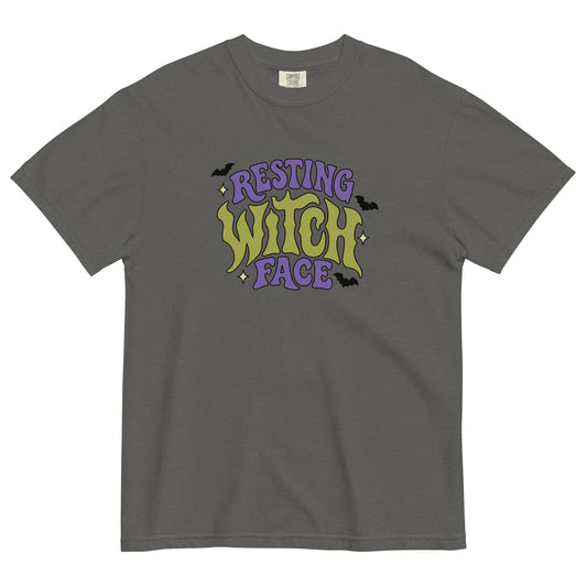 A dark gray crewneck t-shirt featuring a retro-style graphic on the chest that reads 'RESTING WITCH FACE' in purple and lime green gothic lettering, accented with small black bats and stars.
