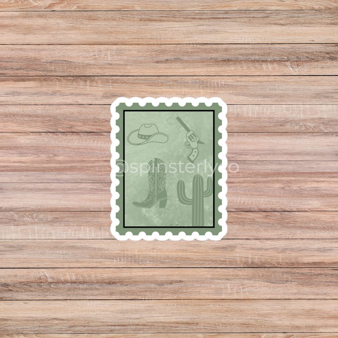 A rectangular postage-stamp-style sticker with a white scalloped border, shown centered on a light brown wood plank background. The sticker has a muted sage green face with western-themed line drawings including a cowboy hat, boots, a revolver, and a cactus.
