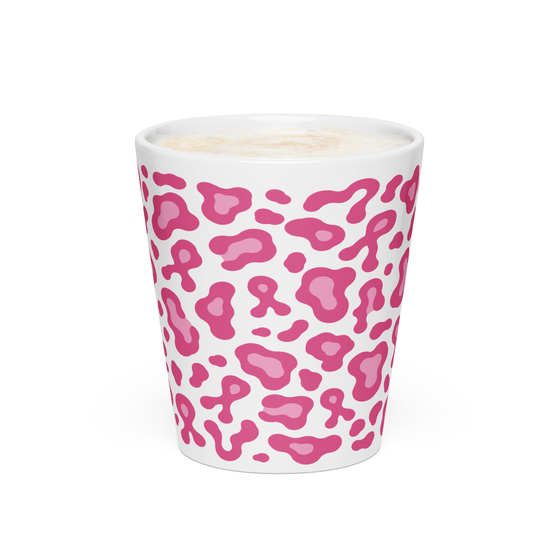 A white ceramic shot glass featuring a pink leopard print pattern, filled with a light-colored beverage and topped with foam, set against a plain white background.