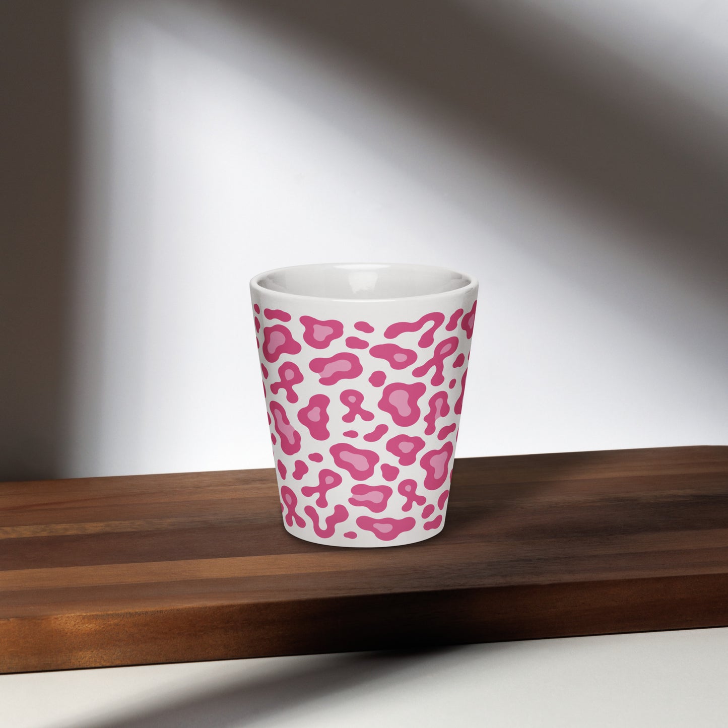 White ceramic cup with a pink leopard print design on a wooden surface