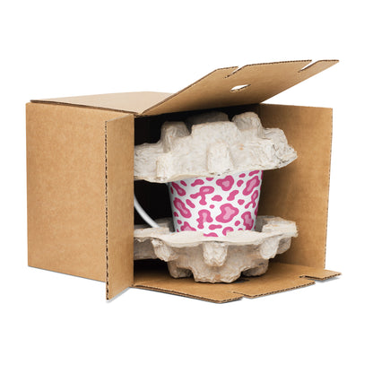 White mug with a colorful design in an open cardboard box with protective wrap.