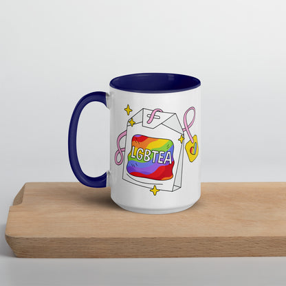White 15oz ceramic LGBTea mug with dark blue handle and interior, featuring a rainbow tea bag illustration with pink ribbons and sparkles.