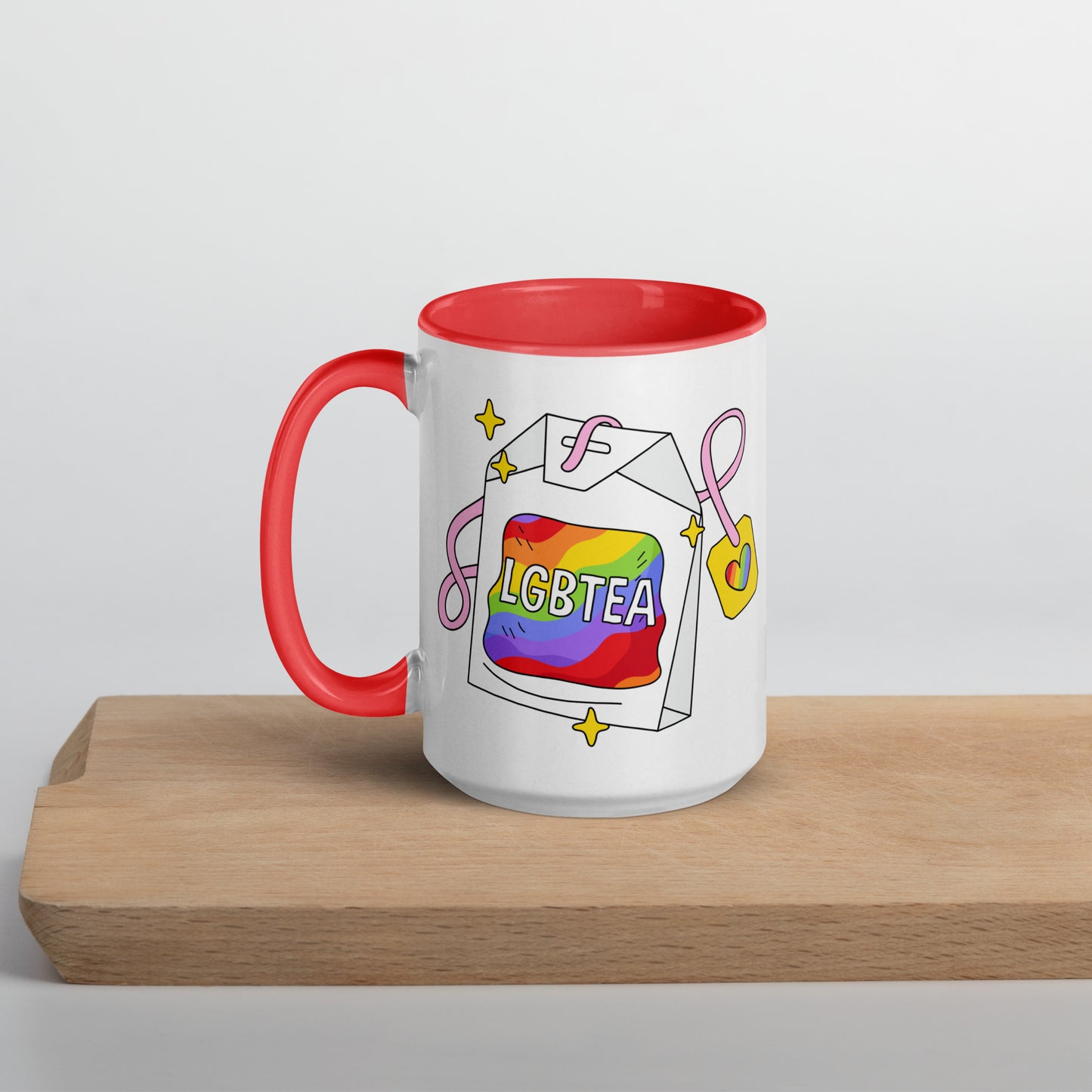 White 15oz ceramic LGBTea mug with red handle and interior, featuring a rainbow tea bag illustration with pink ribbons and sparkles.