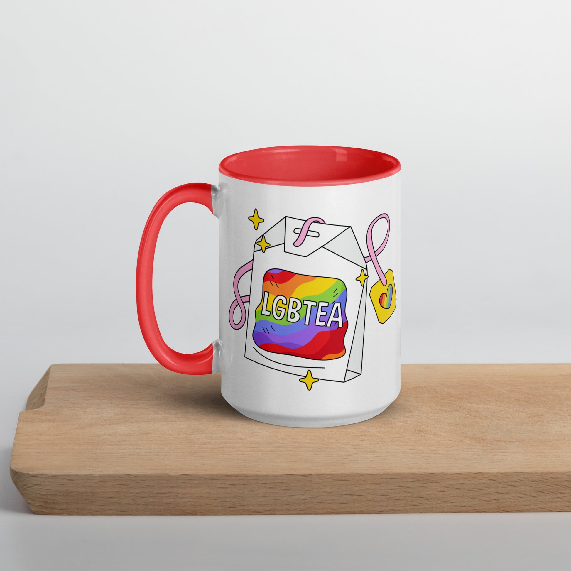 White 15oz ceramic LGBTea mug with red handle and interior, featuring a rainbow tea bag illustration with pink ribbons and sparkles.