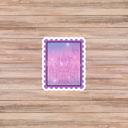 A rectangular die-cut sticker with a purple border and a pink-lavender castle illustration, placed on a light brown wood plank background.