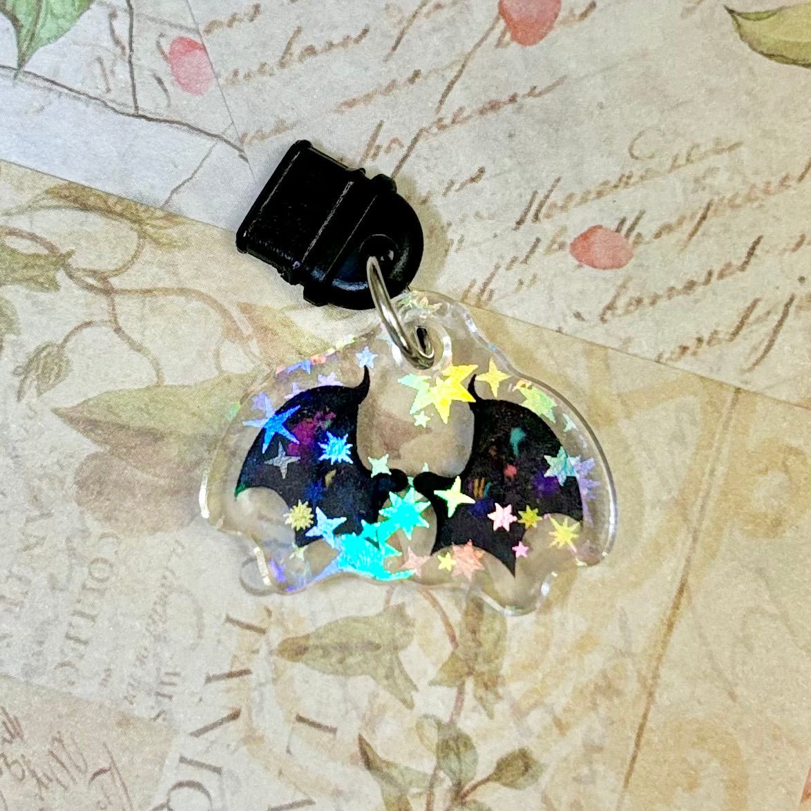 Bat-shaped phone charm with colorful stars on a vintage map background