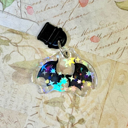Bat-shaped phone charm with colorful stars on a vintage map background