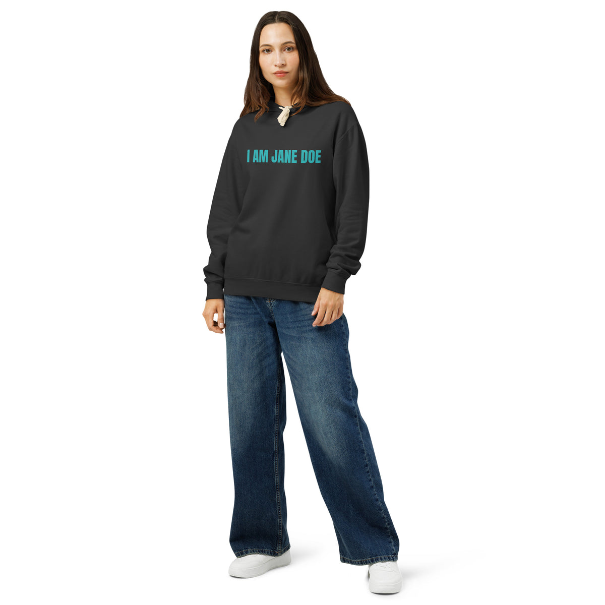 Person wearing a black hoodie with text that reads 'I AM JANE DOE' in bold sans serif font, in teal, standing against a white background