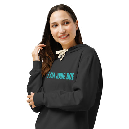 A woman wearing a black pullover hoodie with the text 'I AM JANE DOE' printed in teal across the chest, posed against a solid white background.