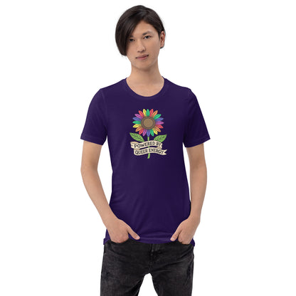 A model wearing a dark blue t-shirt with a colorful rainbow sunflower graphic and the text 'POWERED BY QUEER ENERGY' on the chest, paired with black jeans against a plain white background.