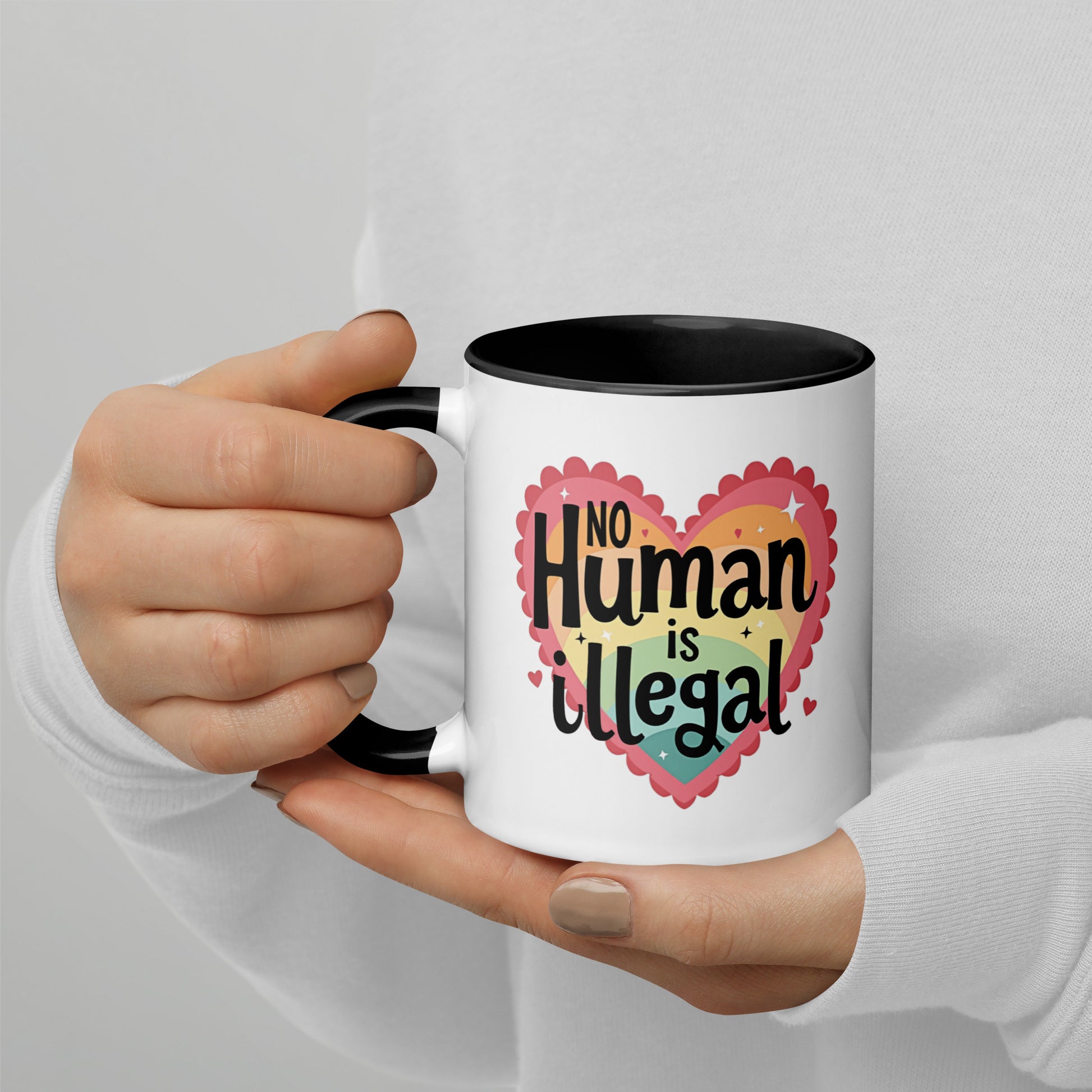 No Human is Illegal Rainbow Heart Accent Coffee Mug by Spinsterly Co, white ceramic with black interior