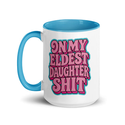 A white ceramic coffee mug with a bright blue handle and interior, featuring a bold pink and blue graphic that reads 'ON MY ELDEST DAUGHTER SHIT' in a retro bubble font.